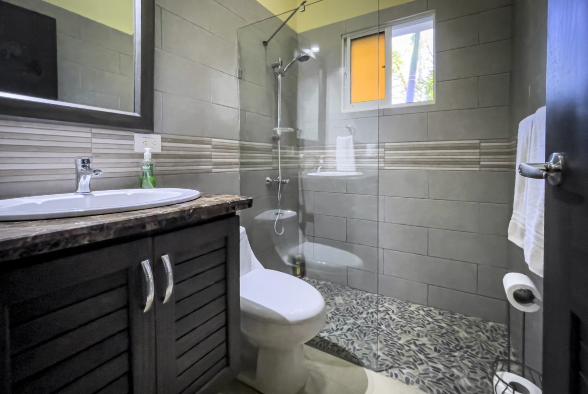 buyDRproperty Modern bathroom in a Stunning 2 Bedroom Villa with gray tile and pebble shower floor. Sosua Real Estate