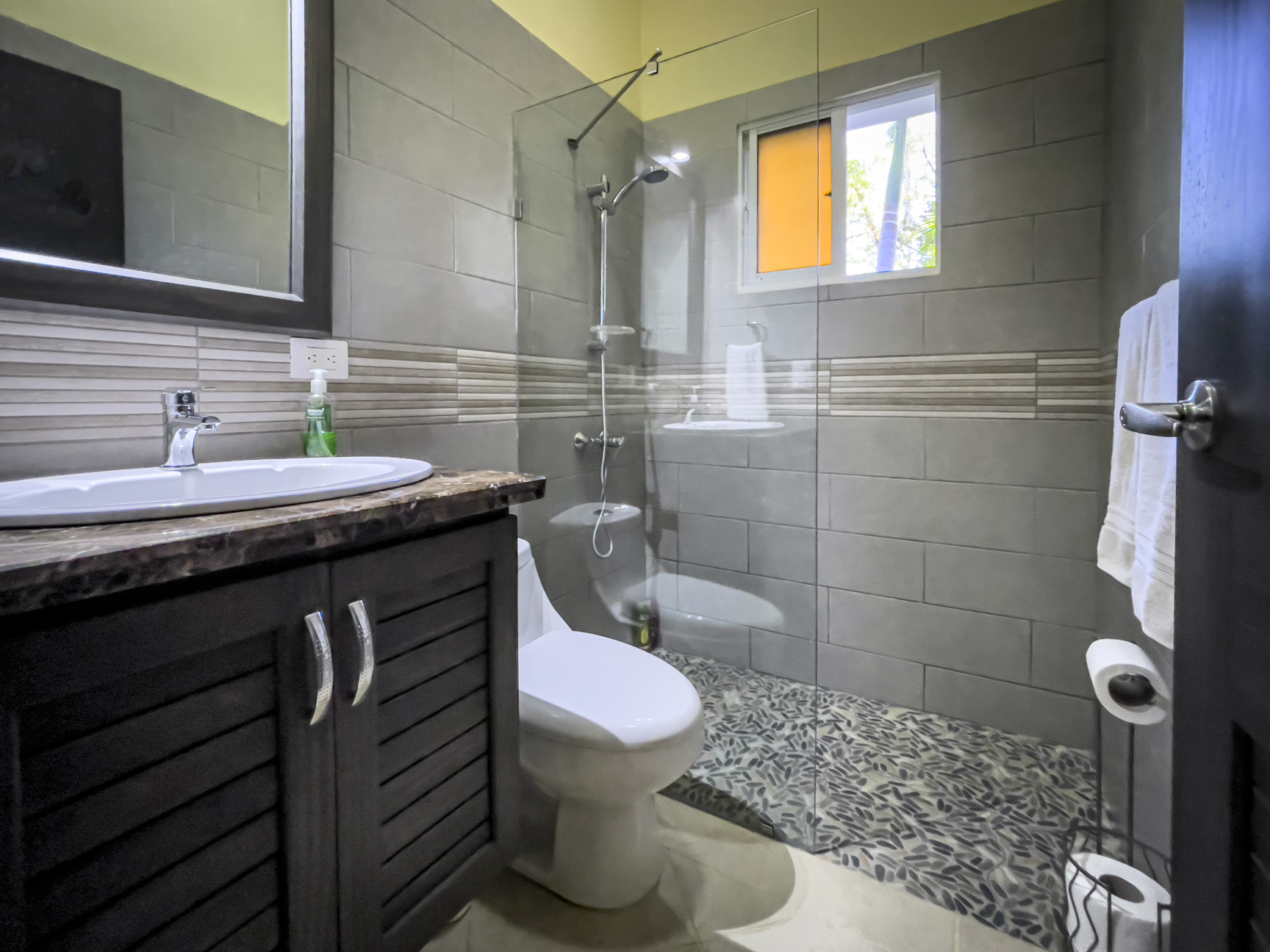 buyDRproperty Modern bathroom in a Stunning 2 Bedroom Villa with gray tile and pebble shower floor. Sosua Real Estate
