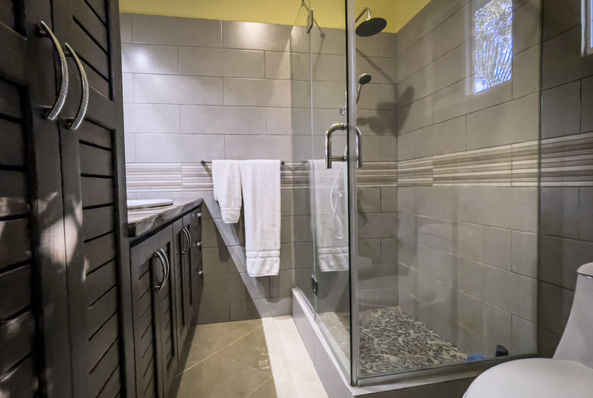 buyDRproperty Modern bathroom in a stunning 2 bedroom villa featuring a glass shower and dark wood vanity. Sosua Real Estate