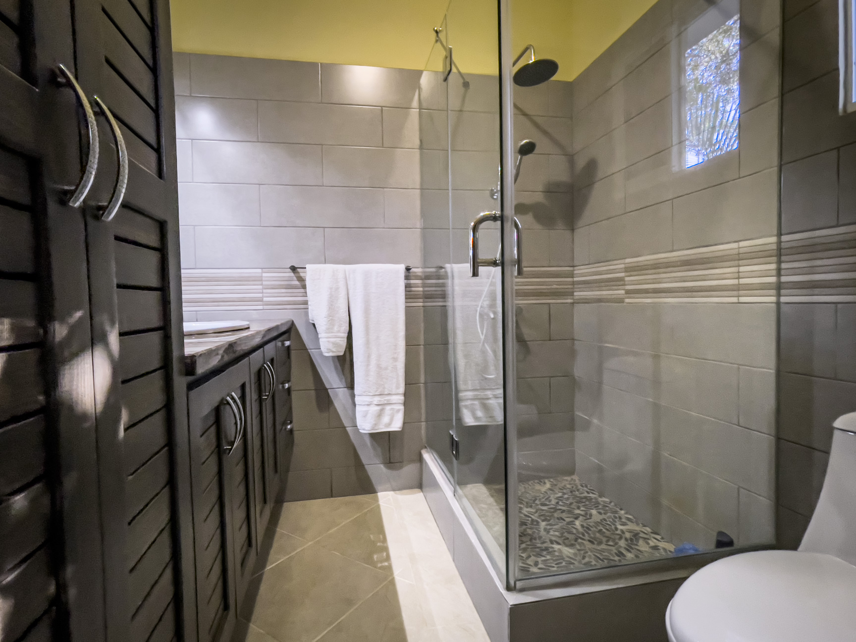 buyDRproperty Modern bathroom in a stunning 2 bedroom villa featuring a glass shower and dark wood vanity. Sosua Real Estate