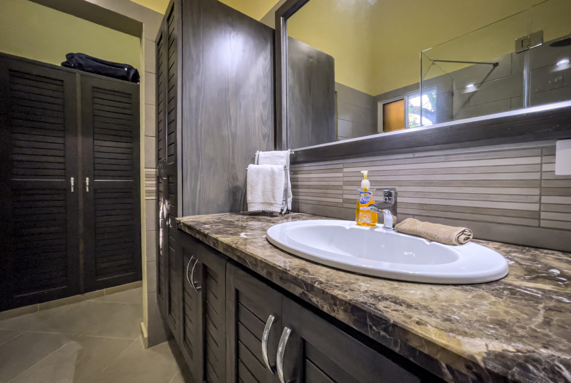 buyDRproperty Bathroom in a stunning 2 bedroom villa with dark wood cabinets, sink, and mirror. Sosua Real Estate