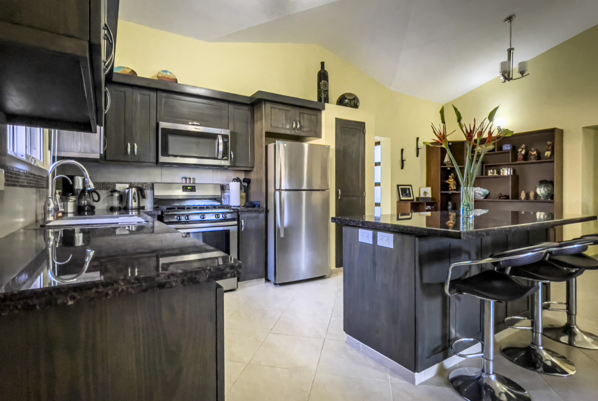 buyDRproperty Modern kitchen in a Stunning 2 Bedroom Villa with dark cabinetry, stainless steel appliances, and a kitchen island. Sosua Real Estate