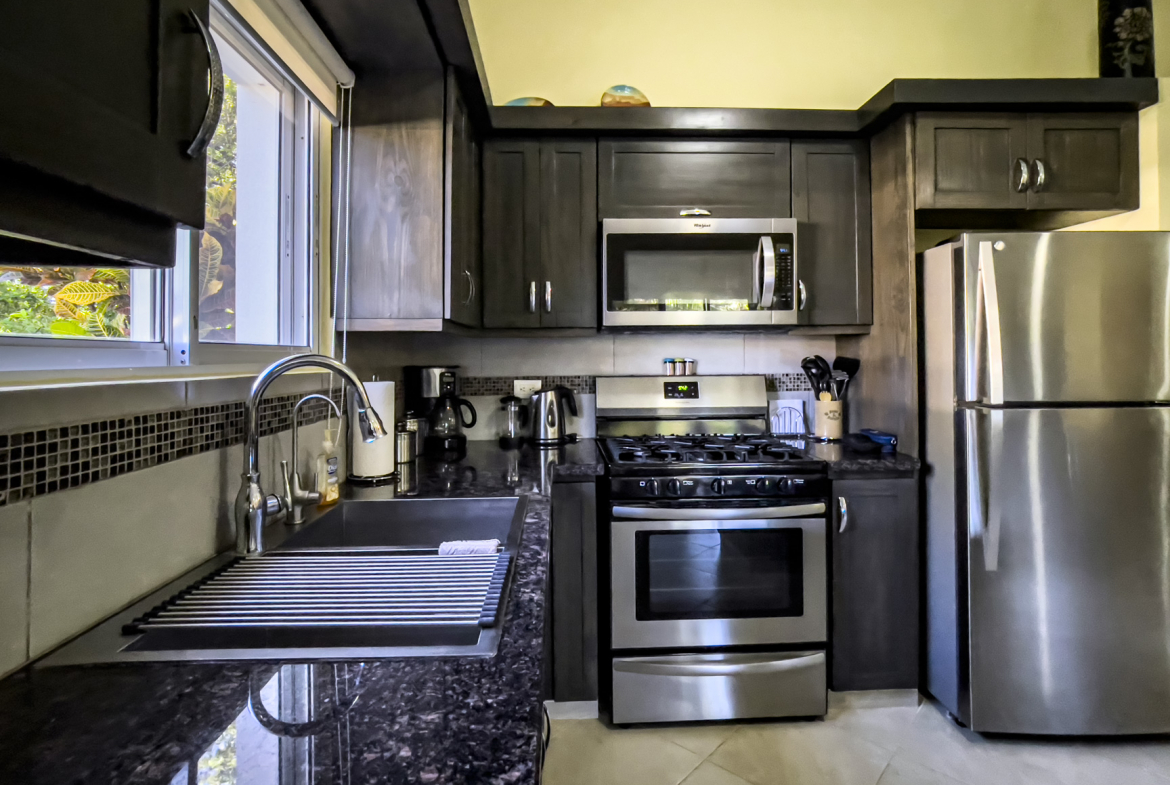 buyDRproperty Modern kitchen with dark cabinets and stainless steel appliances in a Stunning 2 Bedroom Villa. Sosua Real Estate