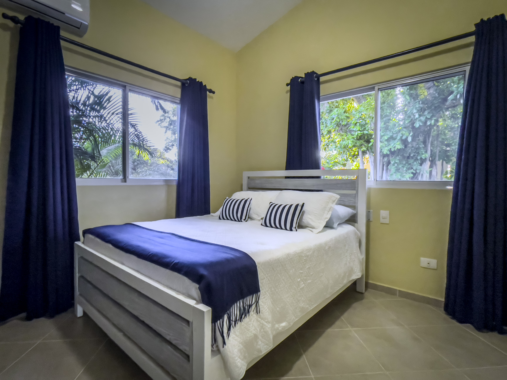 buyDRproperty Bedroom in a Stunning 2 Bedroom Villa with blue curtains and a white bed. Sosua Real Estate