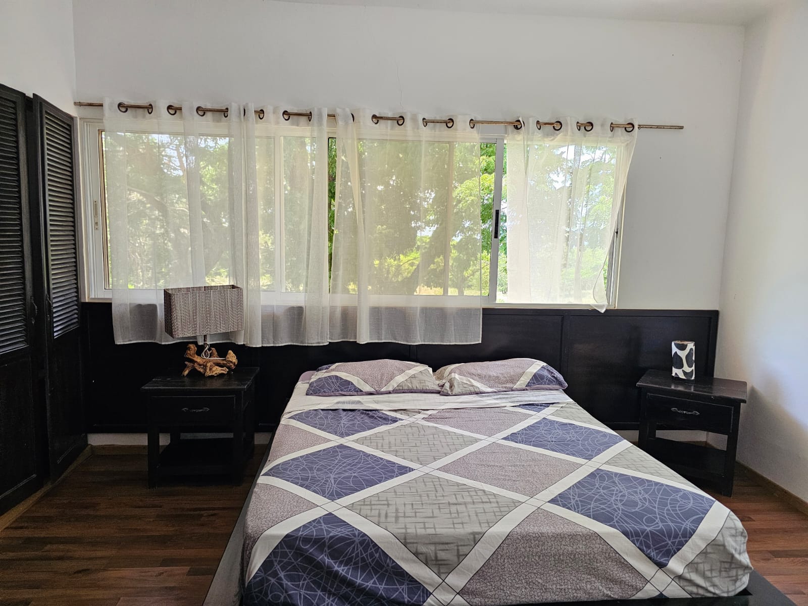 buyDRproperty Bedroom in a unique Sosua villa with a bed, nightstands, and sheer curtains, showcasing beautiful views. Sosua Real Estate