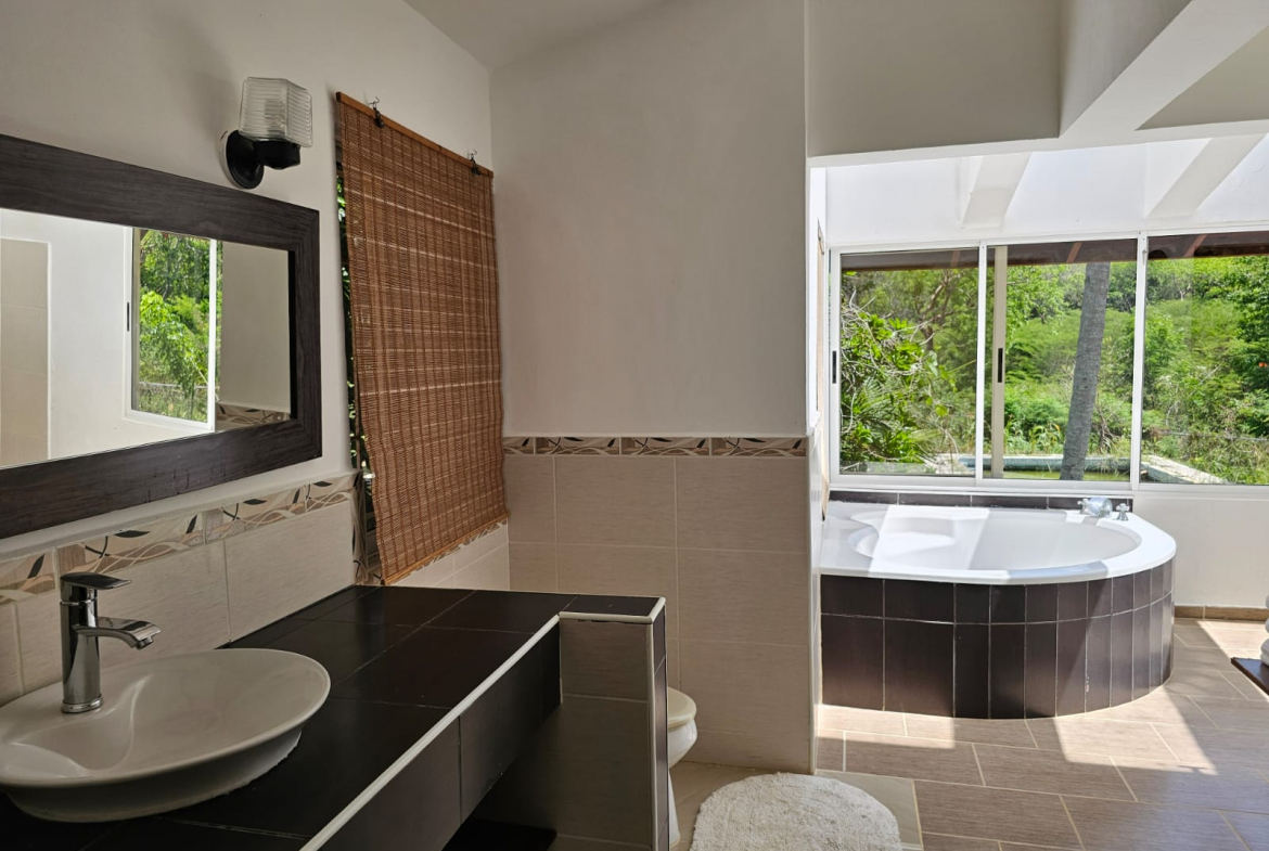 buyDRproperty Bathroom with a unique tub overlooking lush greenery, part of a spacious Sosua villa. Sosua Real Estate