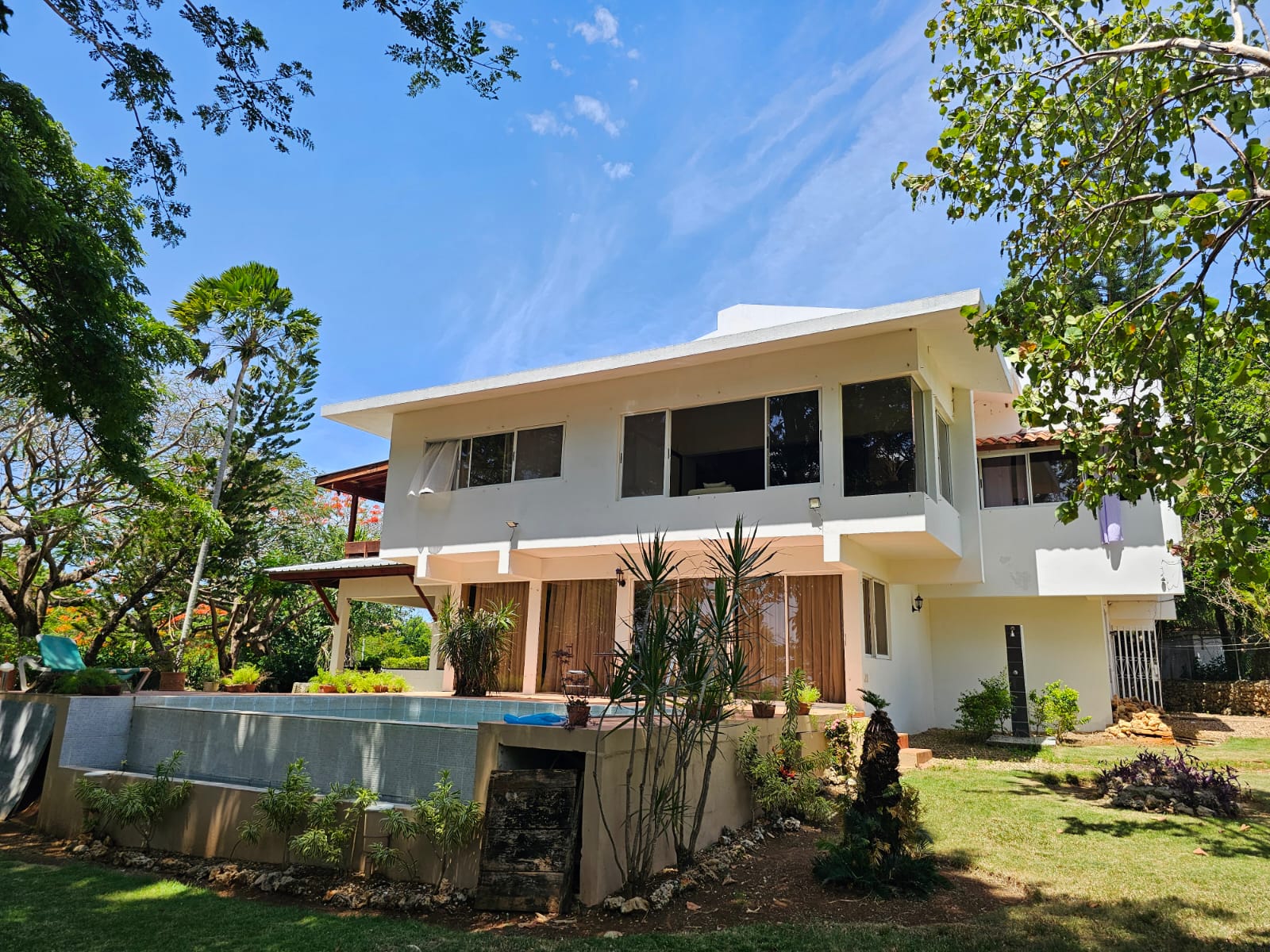 buyDRproperty Exterior view of a unique Sosua villa with a pool and beautiful landscaping. Sosua Real Estate