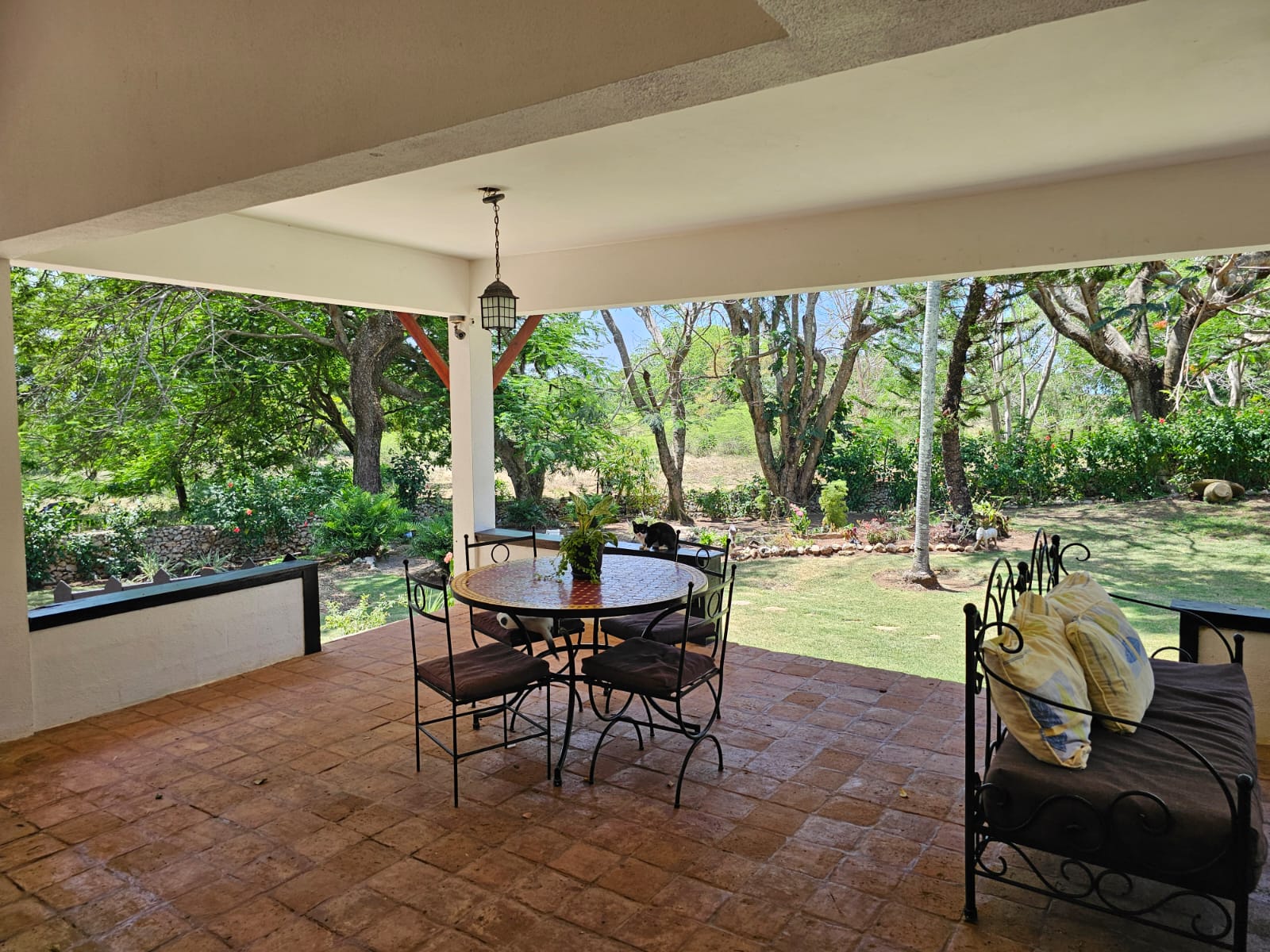 buyDRproperty Covered patio with dining set and daybed overlooking a lush garden at this unique Sosua villa. Sosua Real Estate