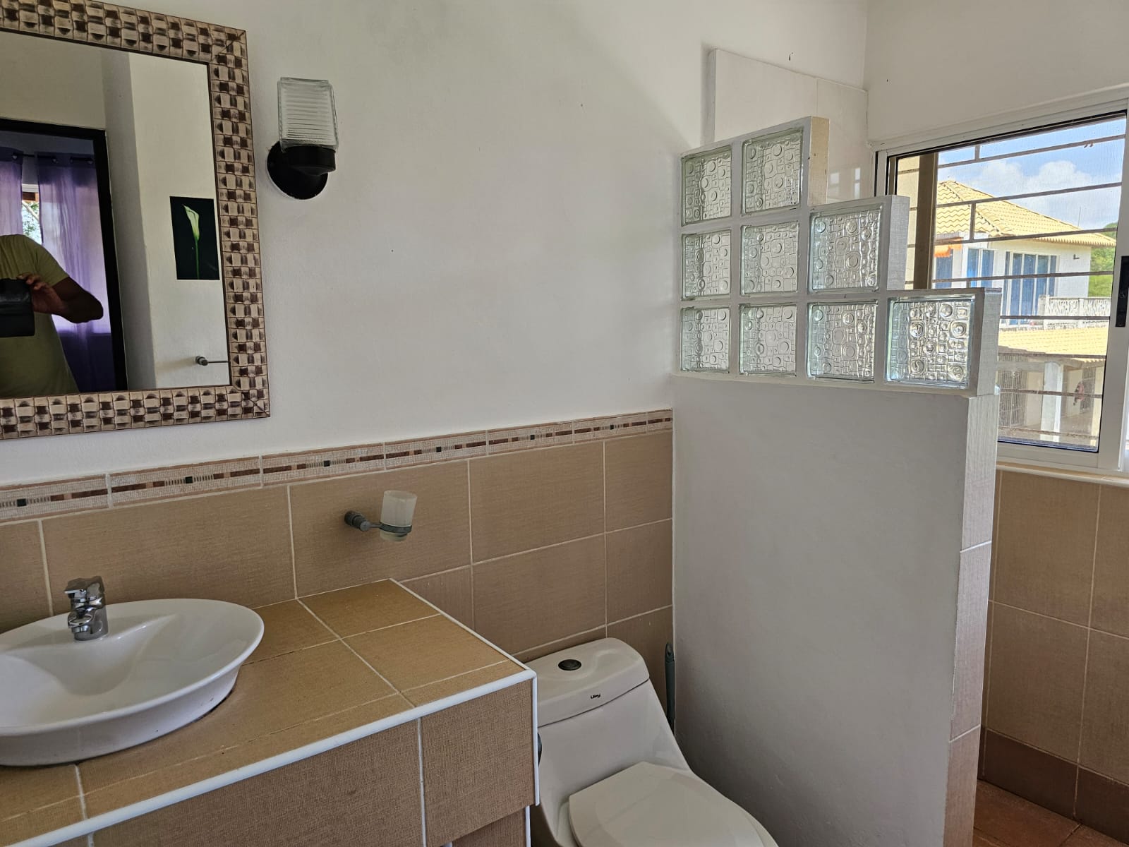 buyDRproperty Bathroom with sink, toilet, window, and decorative glass blocks in a unique Sosua villa. Sosua Real Estate
