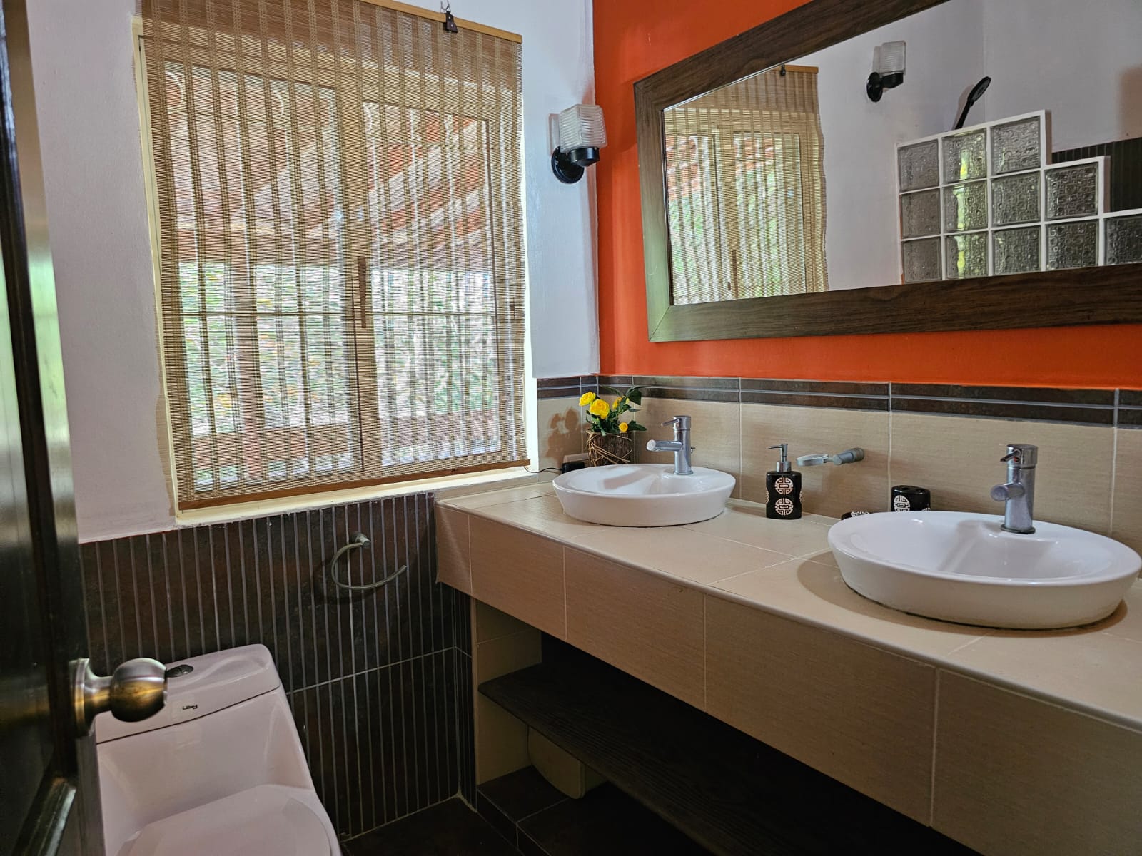 buyDRproperty Bathroom with double sinks, toilet, and window with blinds in a unique Sosua villa. Sosua Real Estate