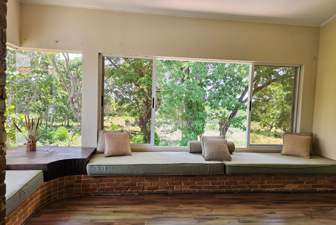 buyDRproperty Cozy window seat with cushions in a unique villa overlooking lush greenery. Sosua Real Estate