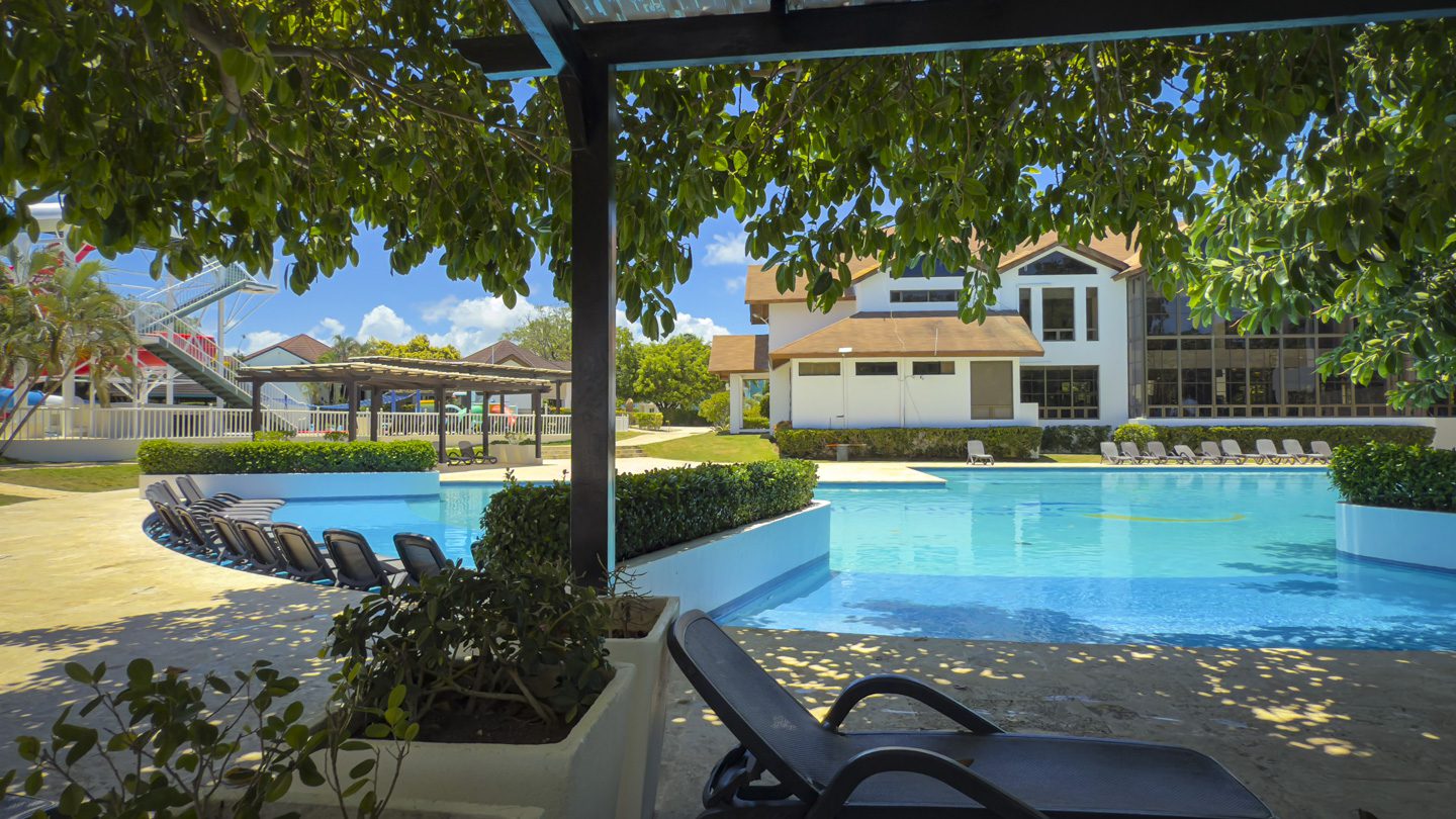 buyDRproperty Pool at Beautiful Modern 3BR Villa Sosua Ocean Village with lounge chairs and greenery. Sosua Real Estate