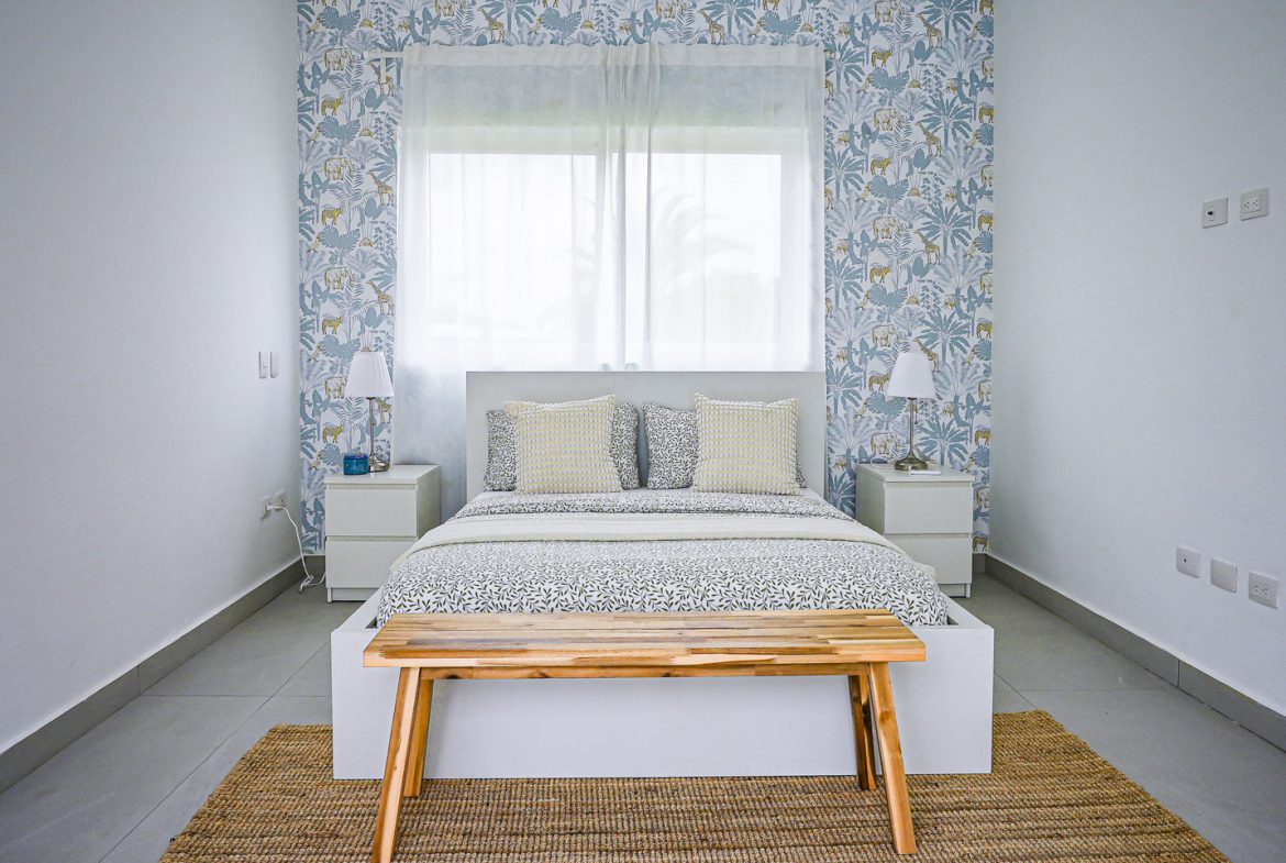 buyDRproperty Modern bedroom with animal print wallpaper, white furniture, and wooden bench. Sosua Real Estate