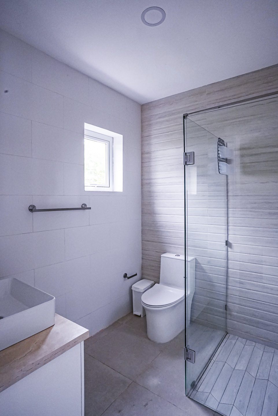 buyDRproperty Modern bathroom with white tile, glass shower, and toilet. Sosua Real Estate