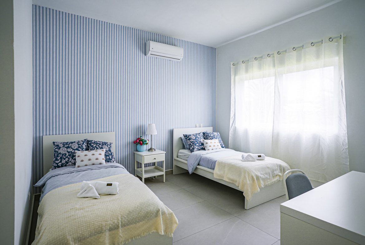 buyDRproperty Modern bedroom with twin beds and blue and white striped wall. Sosua Real Estate
