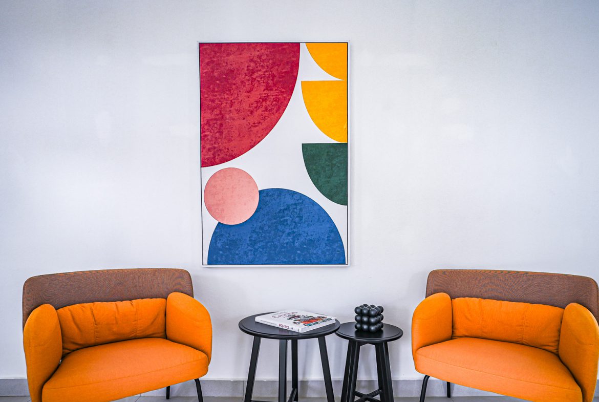 buyDRproperty Modern living room interior with orange armchairs and abstract art. Sosua Real Estate