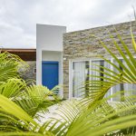 Buydrproperty Modern Villa Exterior with Blue Door and Stone Facade Surrounded by Palm Trees Sosua Real Estate Buydrpropertycom Buydrpropertycom