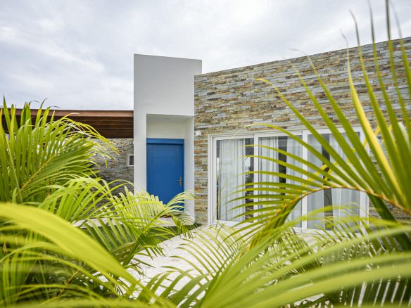 buyDRproperty Modern villa exterior with blue door and stone facade.