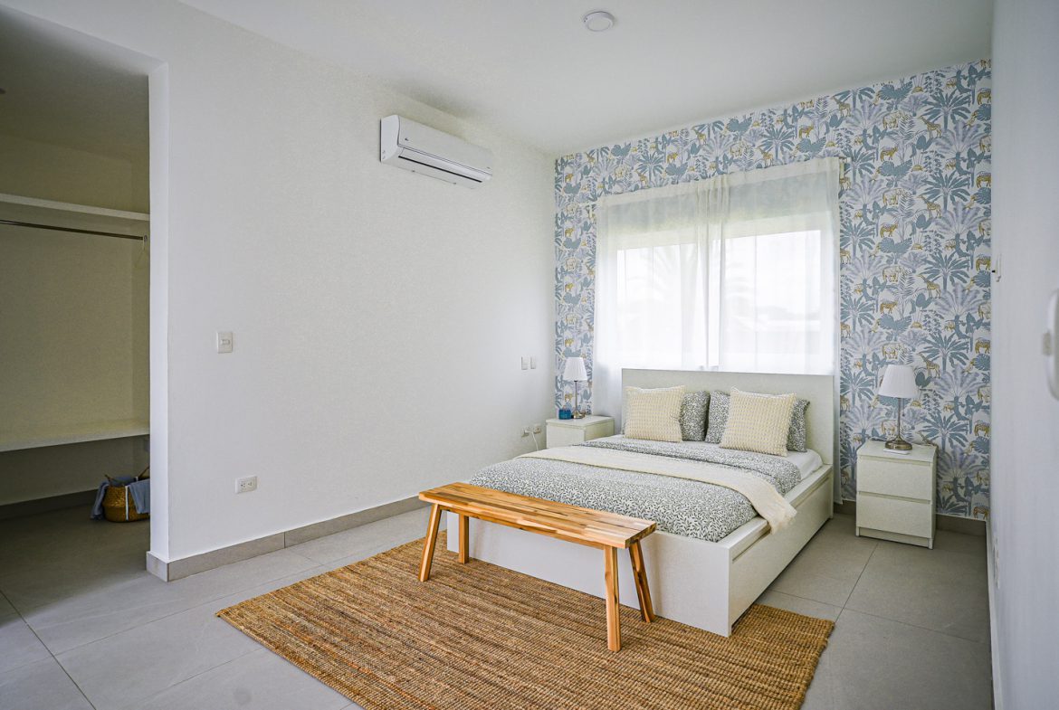 buyDRproperty Modern bedroom with a bed, wallpaper, and rug in a Sosua villa. Sosua Real Estate