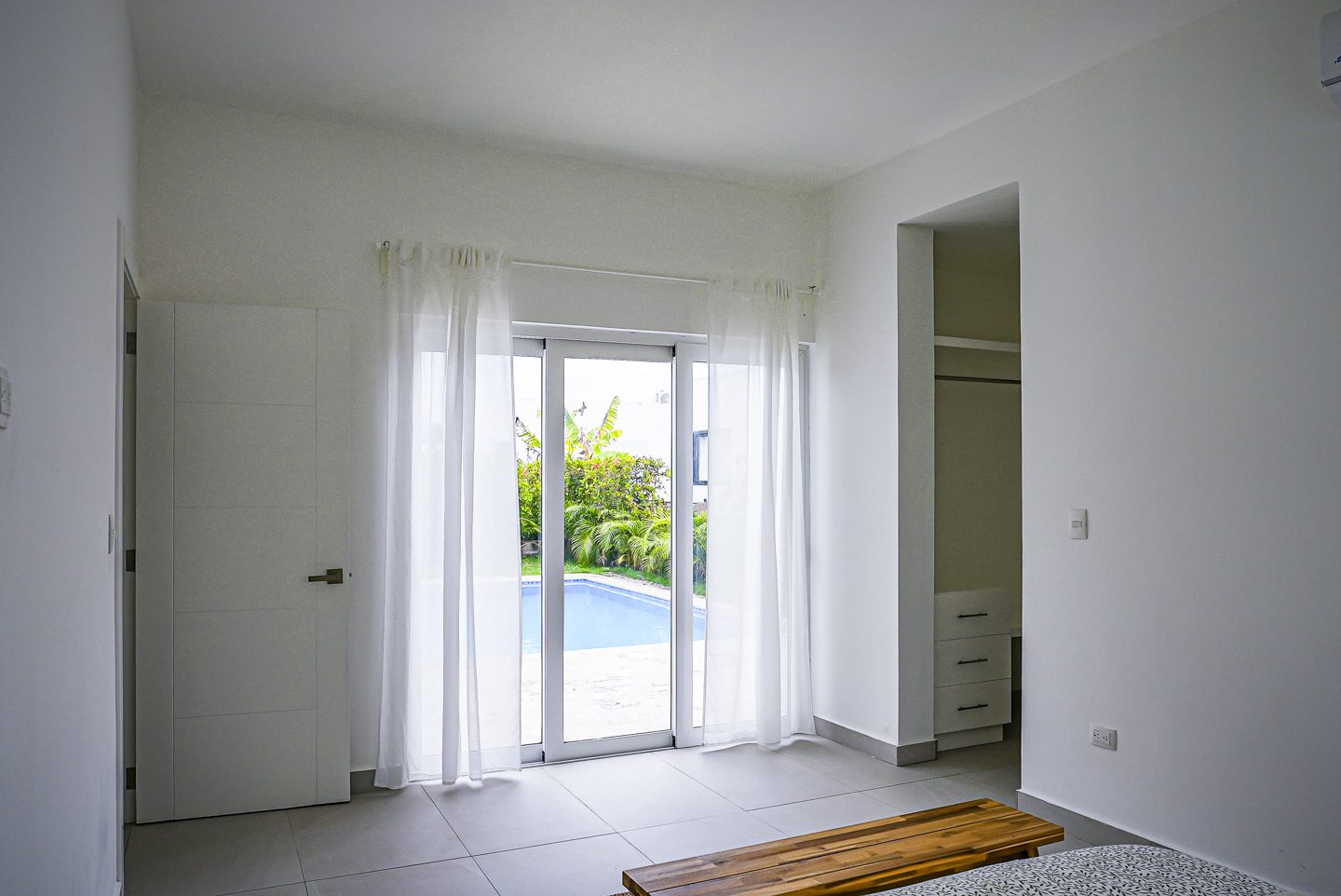 buyDRproperty Modern villa interior with pool view and sheer curtains. Sosua Real Estate