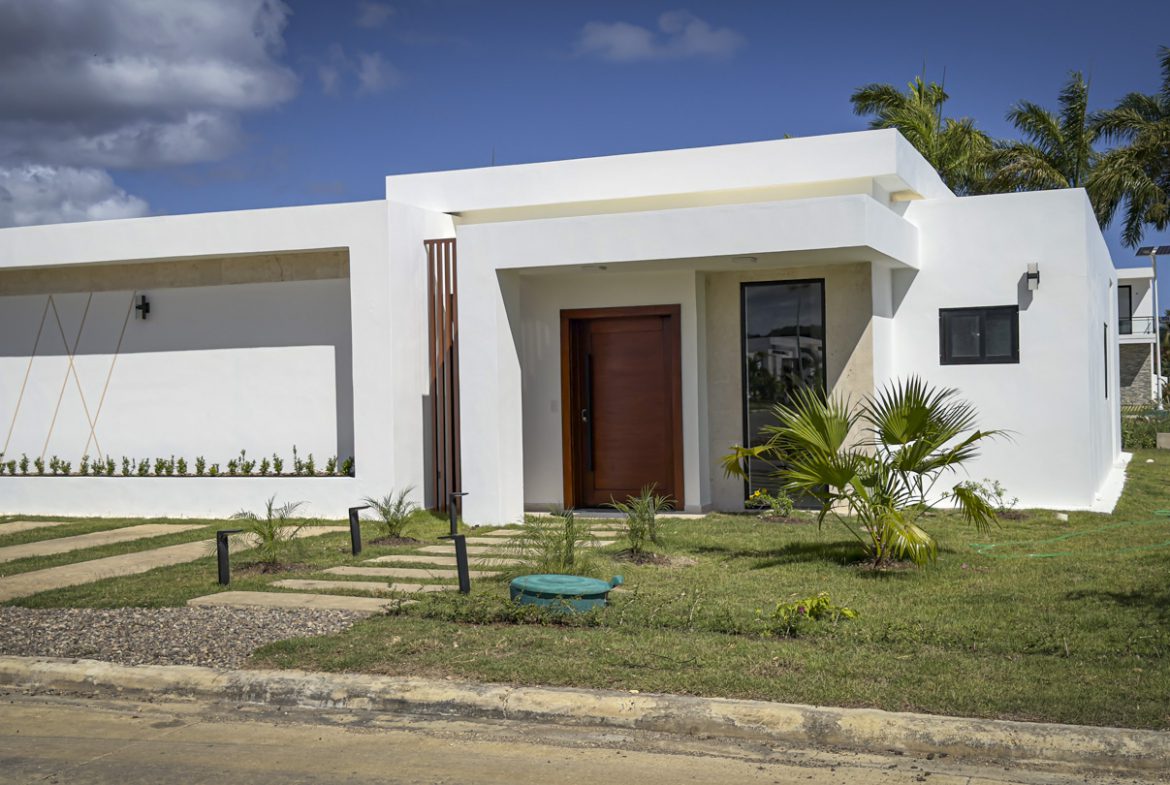 buyDRproperty Modern white villa with wooden door and green lawn in Sosua Ocean Village. Sosua Real Estate