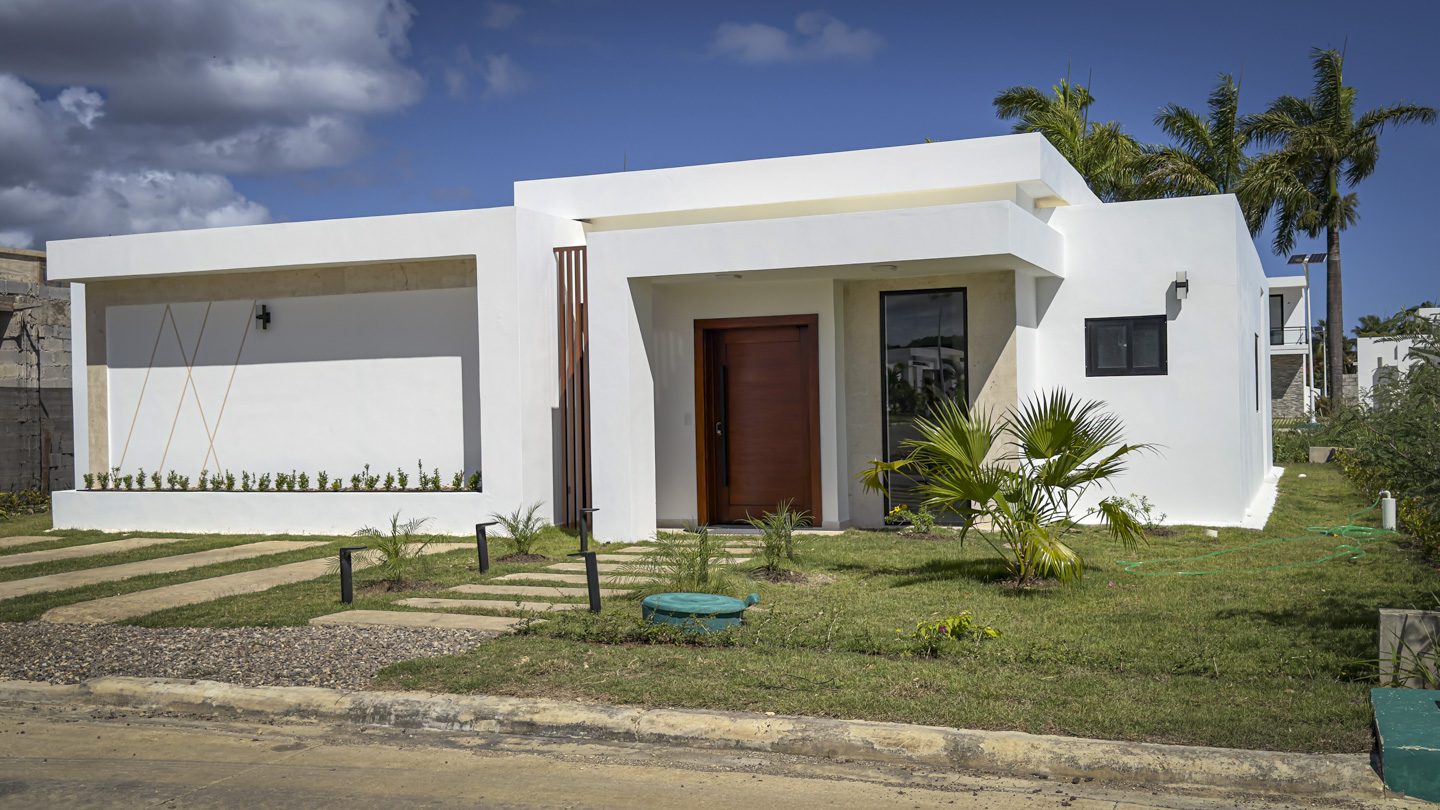 buyDRproperty Modern white villa with wooden door and green lawn in Sosua Ocean Village. Sosua Real Estate
