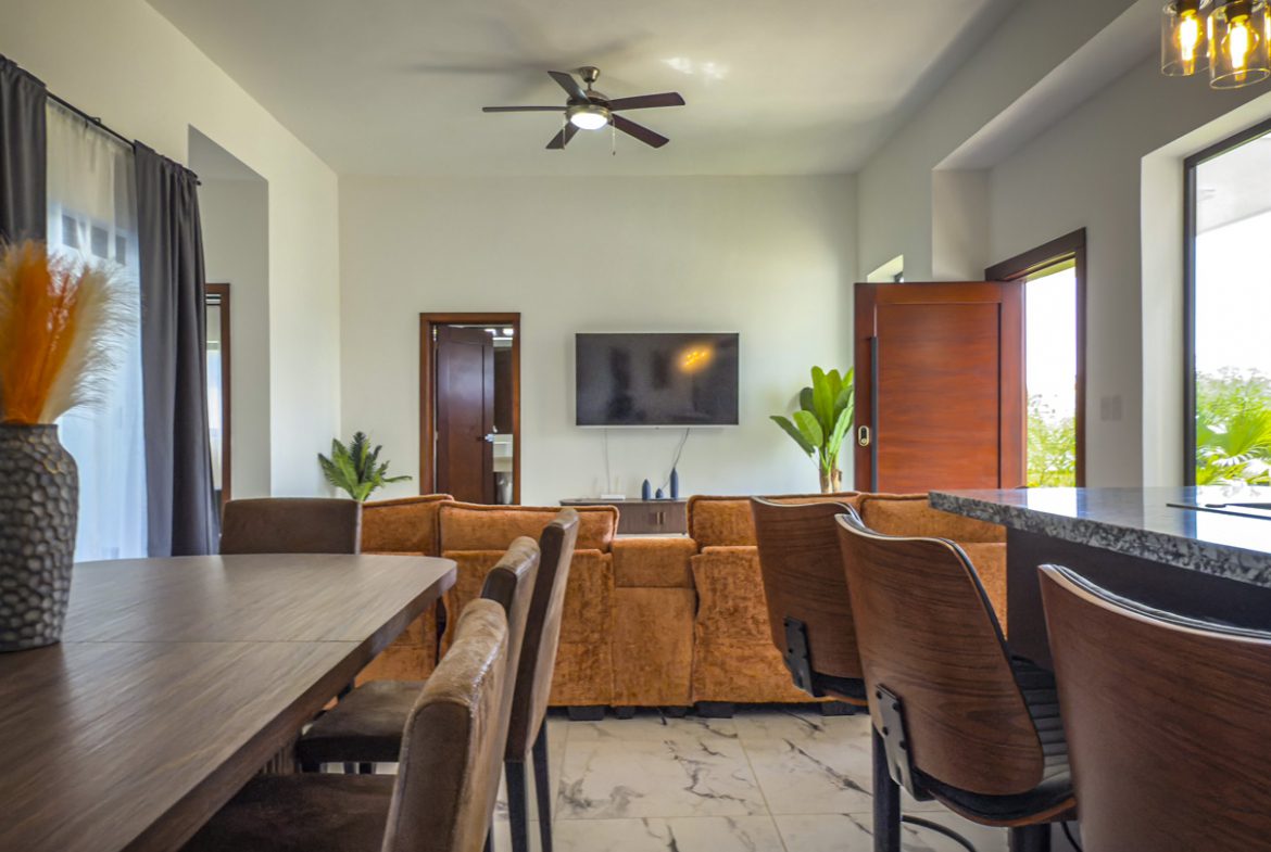 buyDRproperty Modern villa living room with dining area, sofa, and kitchen island. Sosua Real Estate