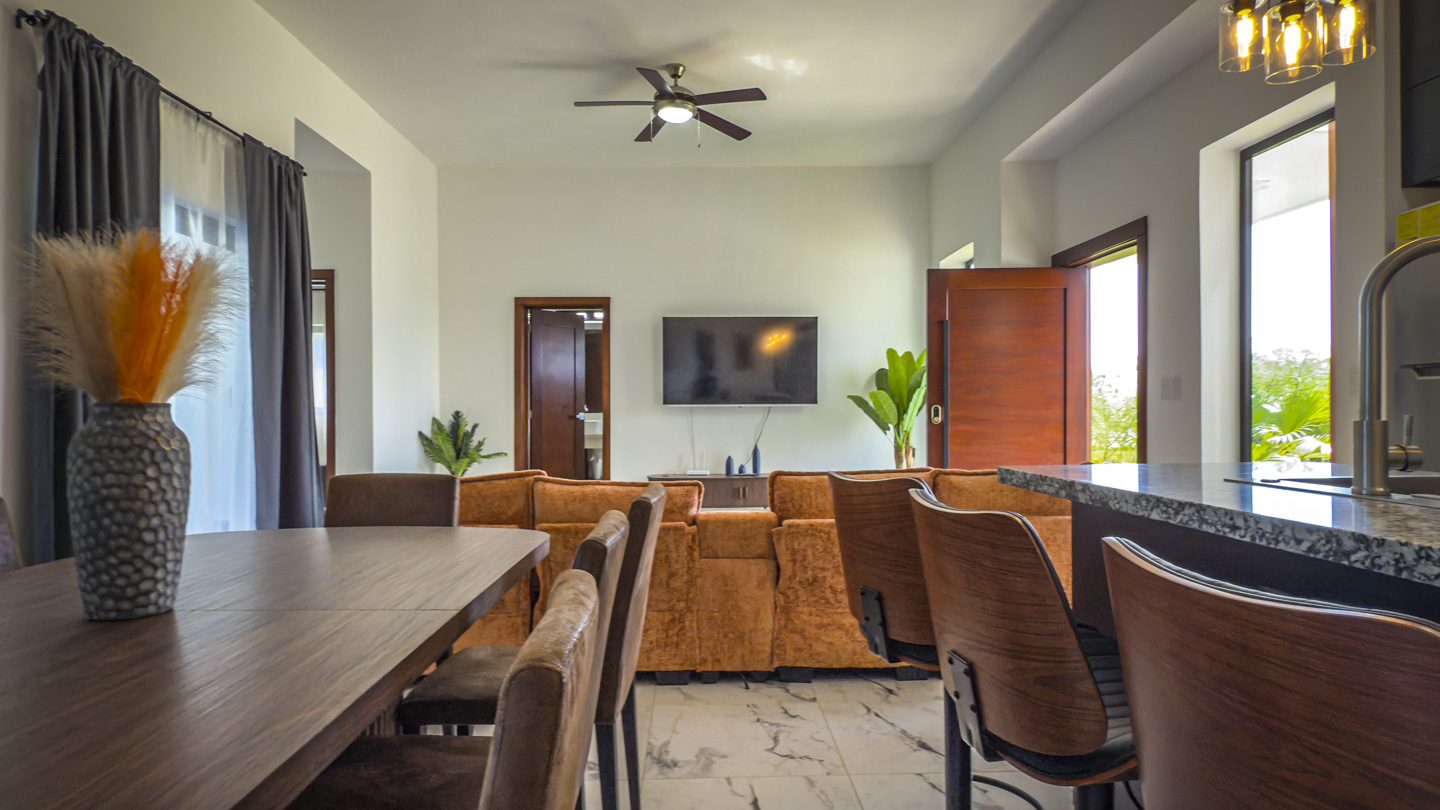 buyDRproperty Modern villa living room with dining area, sofa, and kitchen island. Sosua Real Estate