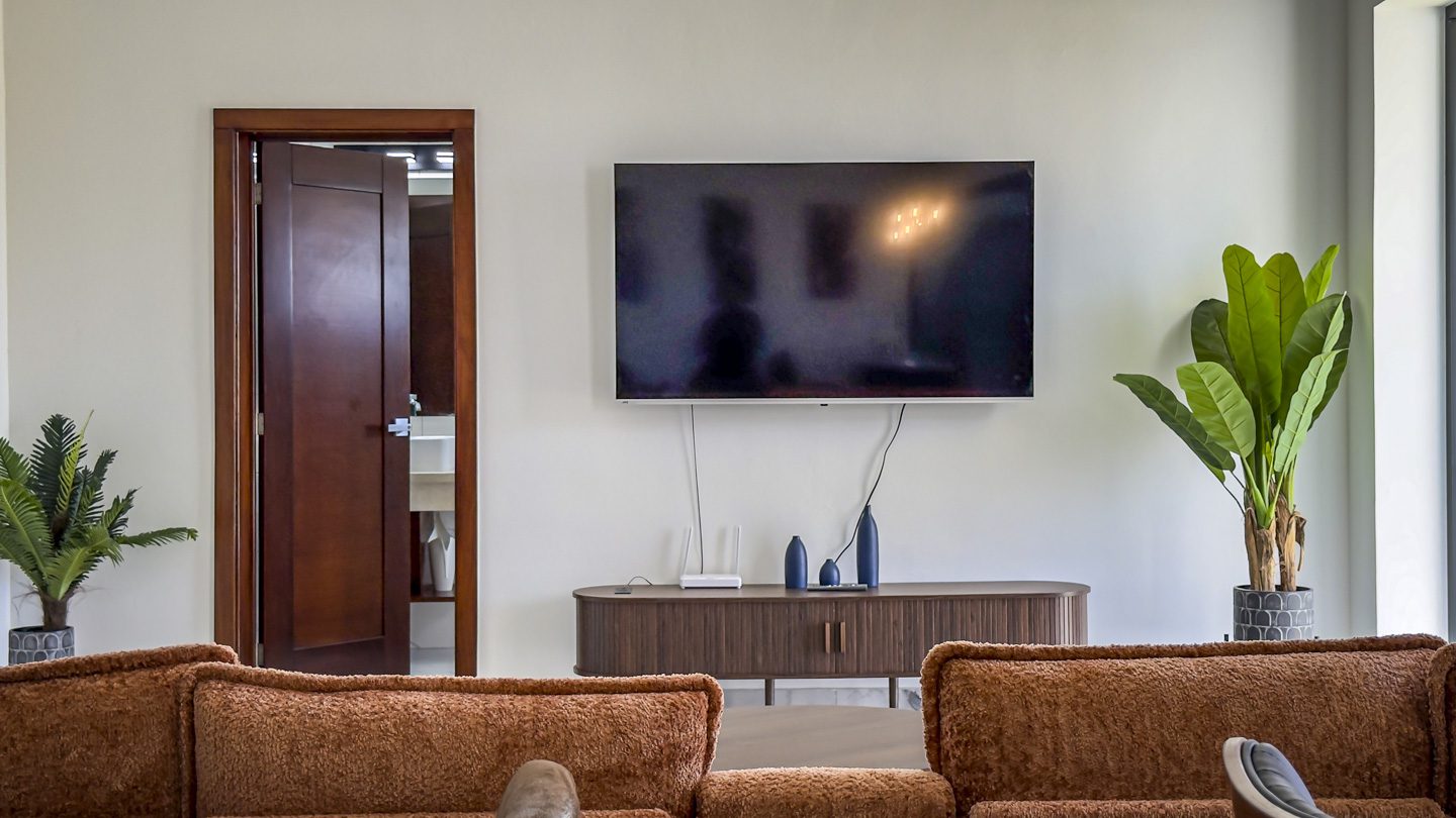 buyDRproperty Modern living room with TV, plants, and a glimpse of the bathroom in a Sosua Ocean Village villa. Sosua Real Estate