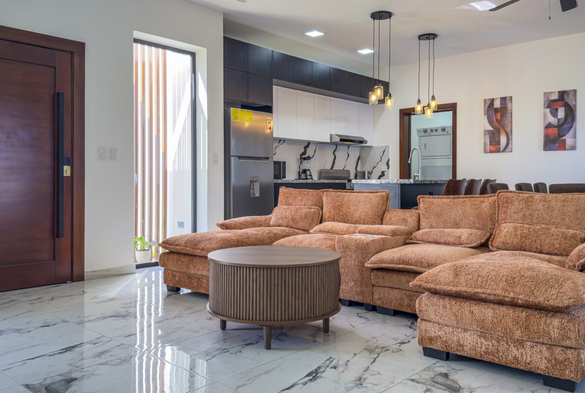buyDRproperty Modern open-plan living room in a 3BR Villa Sosua Ocean Village with brown sectional sofa and marble flooring. Sosua Real Estate