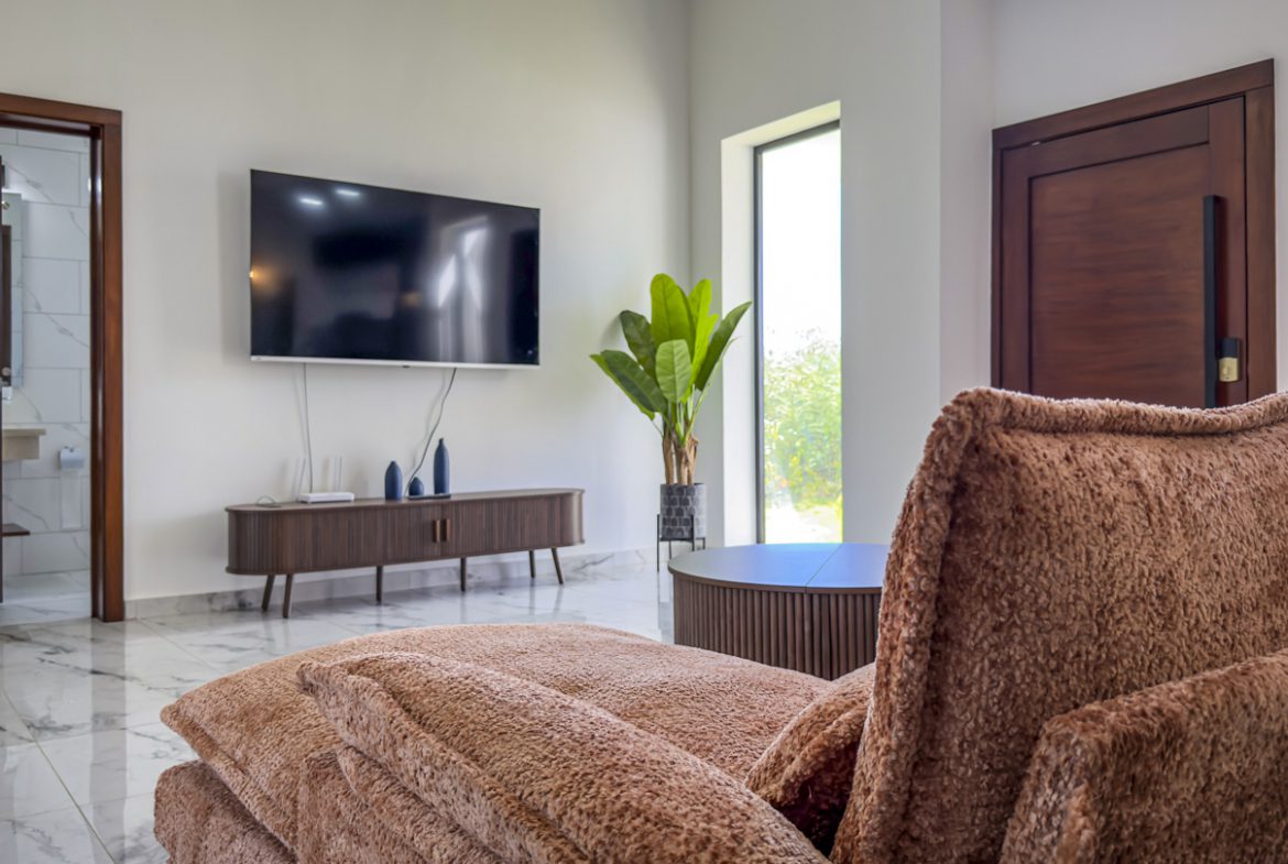 buyDRproperty Modern living room with TV, sofa, and plant in a villa. Sosua Real Estate