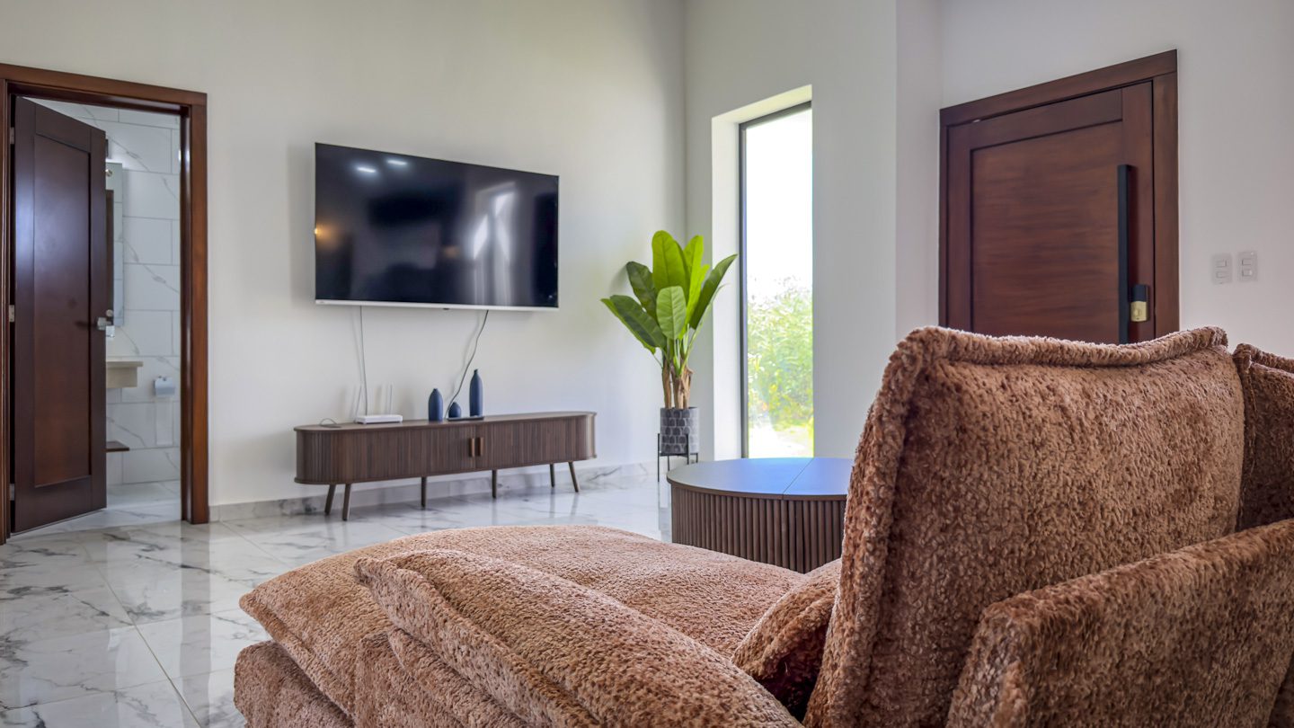 buyDRproperty Modern living room with TV, sofa, and plant in a villa. Sosua Real Estate