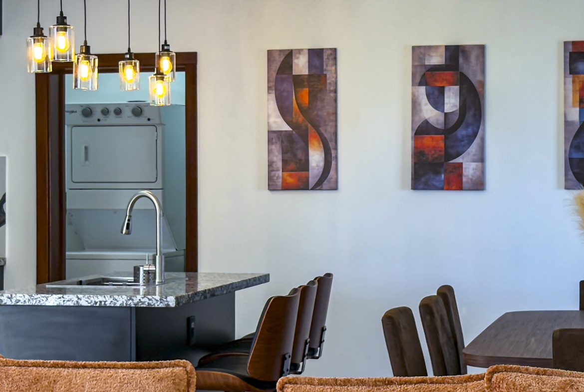 buyDRproperty Modern kitchen with granite countertop, pendant lights, and abstract artwork in a Sosua Ocean Village villa. Sosua Real Estate