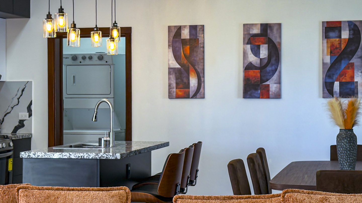 buyDRproperty Modern kitchen with granite countertop, pendant lights, and abstract artwork in a Sosua Ocean Village villa. Sosua Real Estate