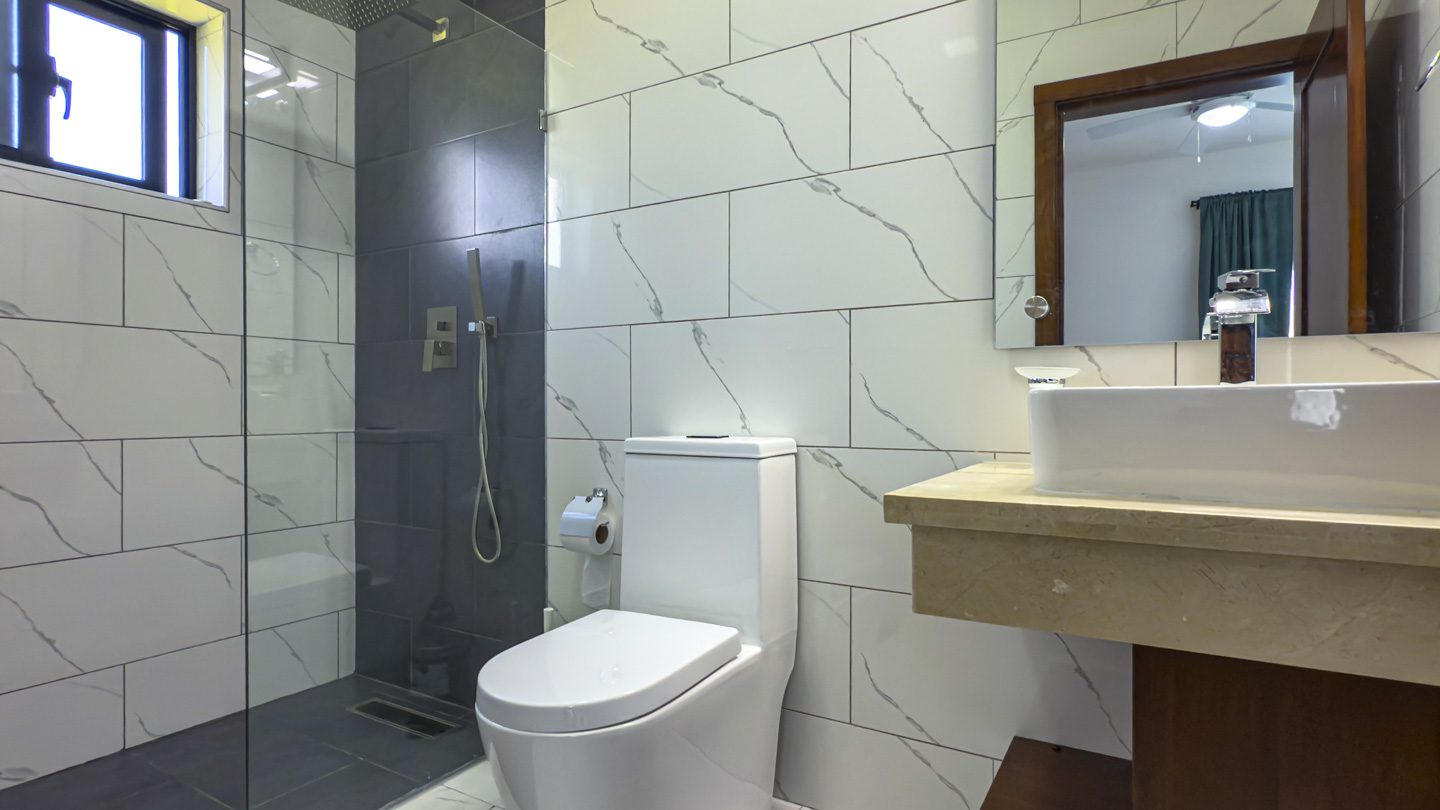 buyDRproperty Modern bathroom design in a Sosua ocean village villa featuring a sleek shower, toilet, and sink. Sosua Real Estate