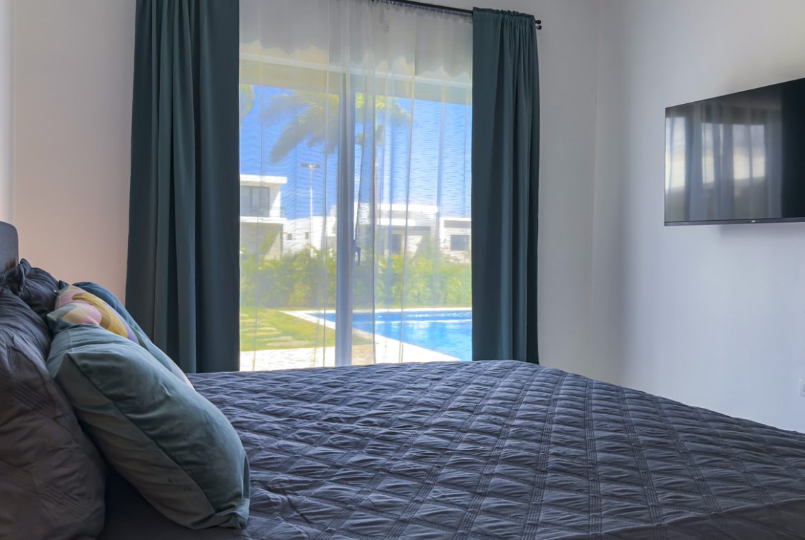 buyDRproperty Bedroom with a view of a pool in a modern villa. Sosua Real Estate