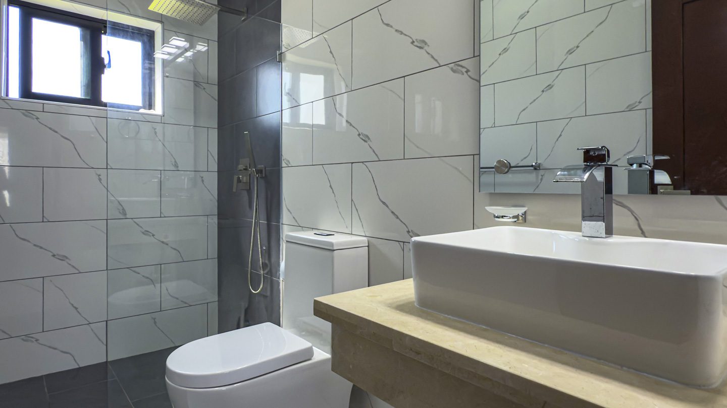 buyDRproperty Modern bathroom with white marble tiles and rectangular sink in Sosua Ocean Village villa. Sosua Real Estate