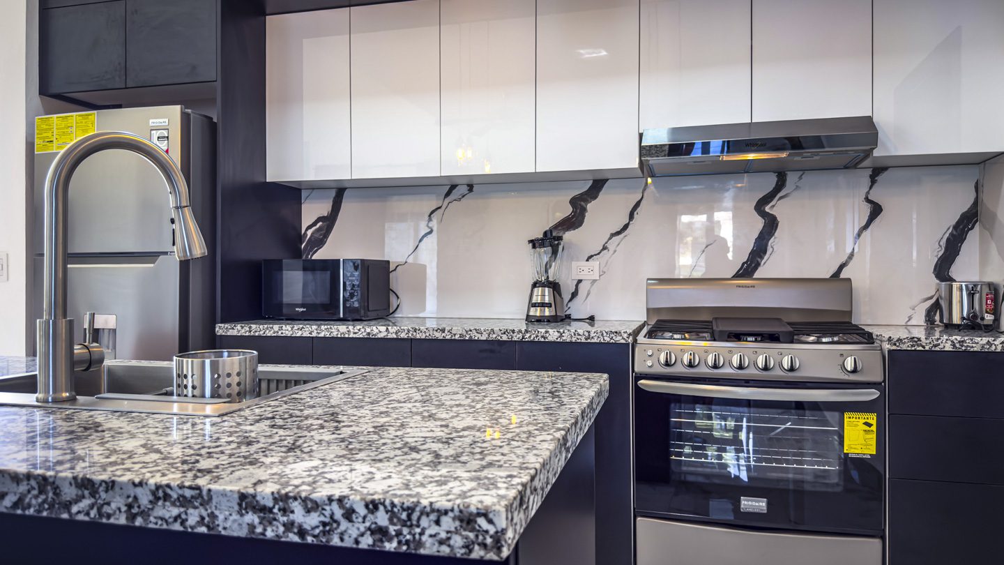 buyDRproperty Modern kitchen with white cabinets, granite countertops, and stainless steel appliances. Sosua Real Estate