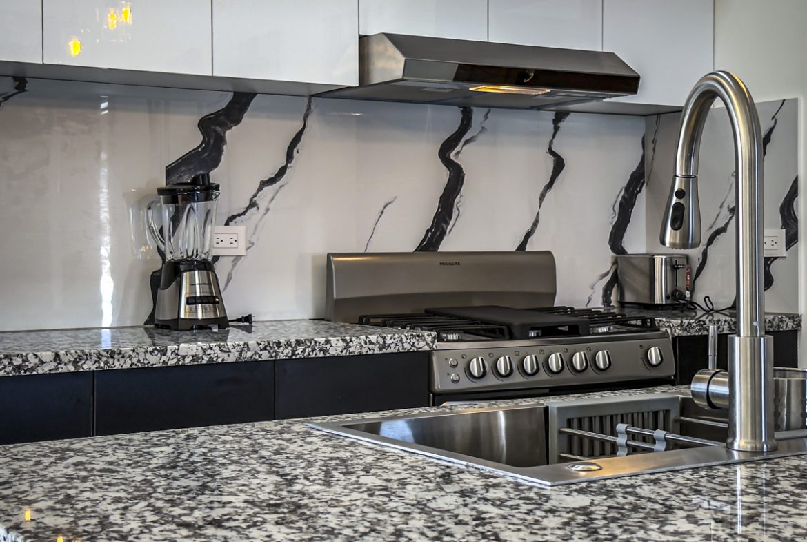 buyDRproperty Modern kitchen with granite counters, stainless steel appliances, and marble backsplash. Sosua Real Estate