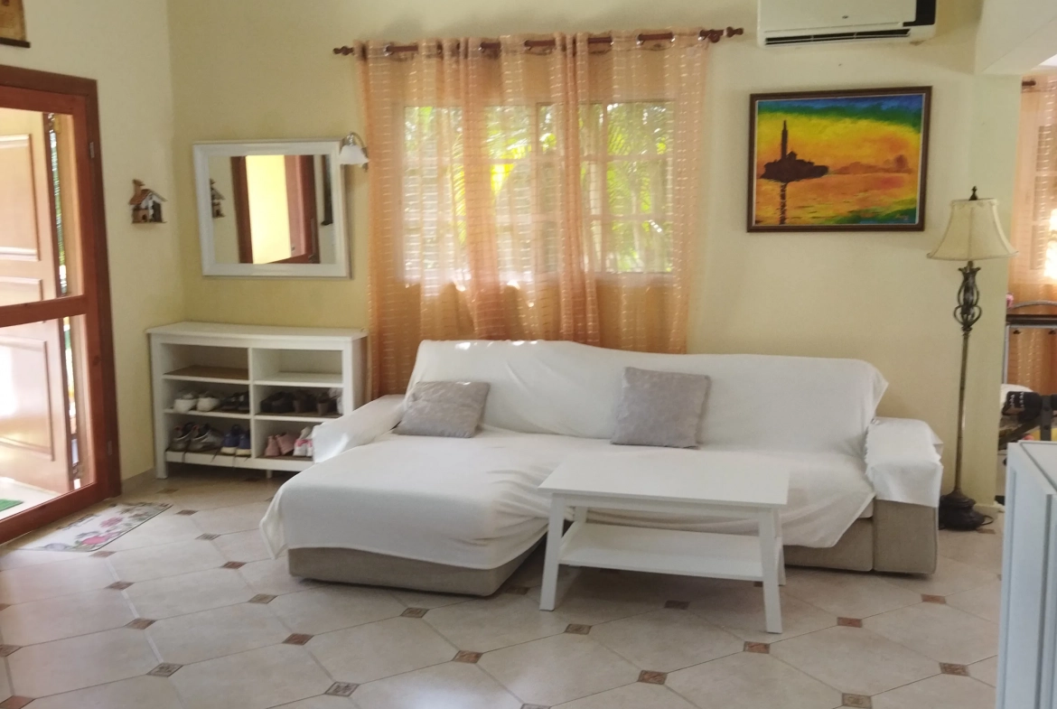 buyDRproperty Charming living room in a villa for sale, featuring a sofa, coffee table, and artwork. Sosua Real Estate