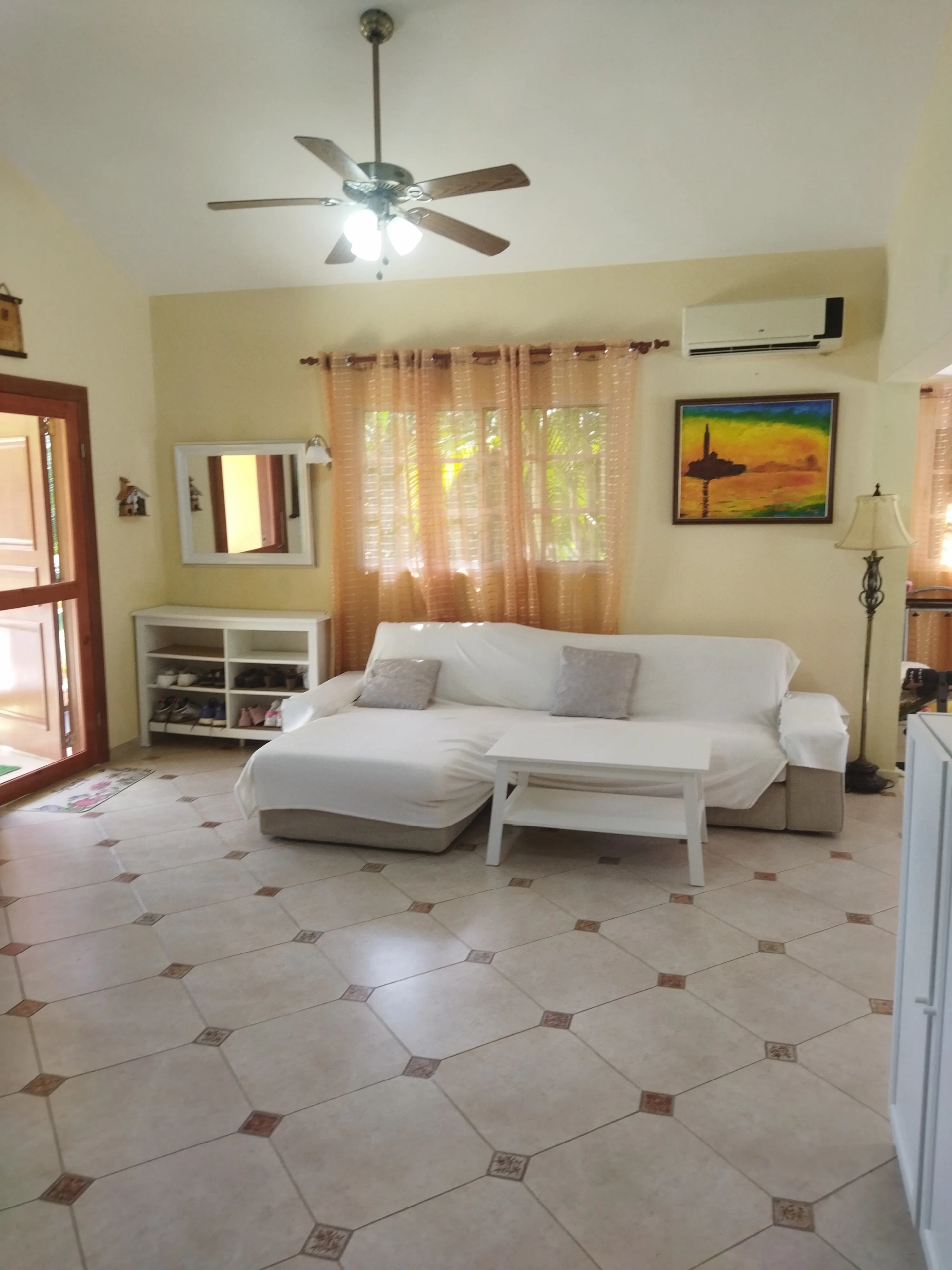 buyDRproperty Charming living room in a villa for sale, featuring a sofa, coffee table, and artwork. Sosua Real Estate