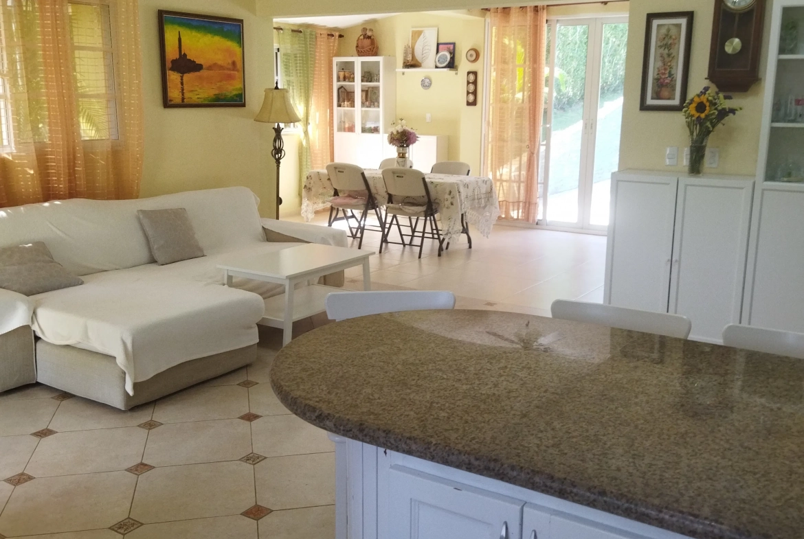 buyDRproperty Charming interior of a villa with white sofa, kitchen island, and dining area. Sosua Real Estate