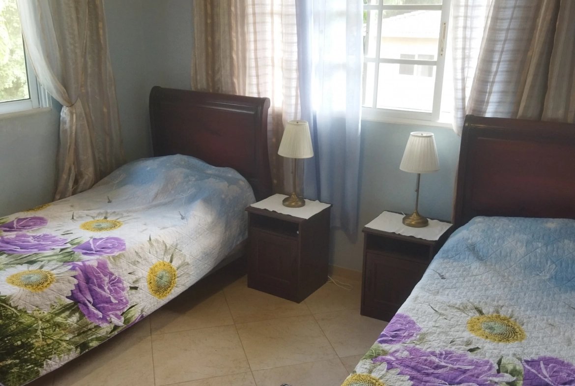 buyDRproperty Charming bedroom with two beds and floral bedspreads. Sosua Real Estate