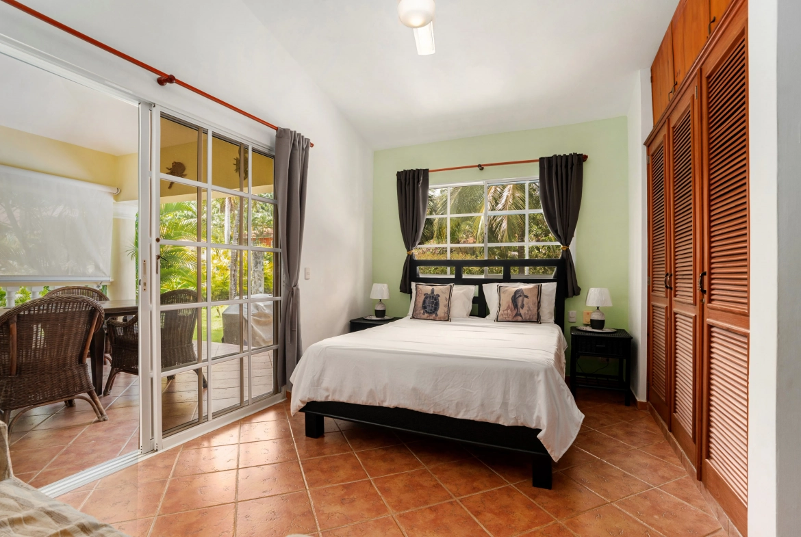 buyDRproperty Bedroom in a Sosua villa for sale with bed, nightstands, and sliding door to outdoor space. Sosua Real Estate
