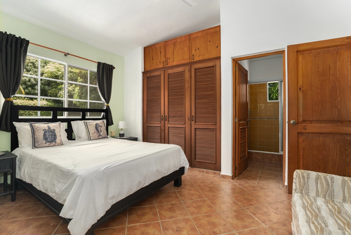 buyDRproperty Bedroom in a Sosua villa for sale, featuring a bed, wardrobe, and bathroom access. Sosua Real Estate