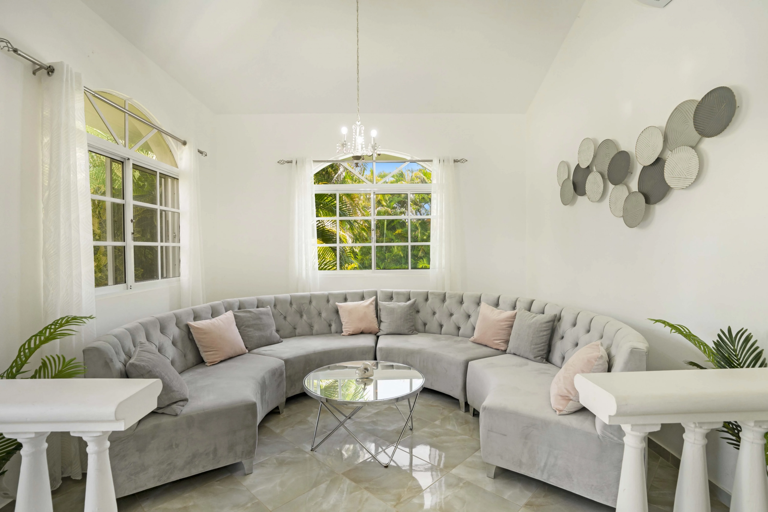 buyDRproperty Beautiful living room with curved gray sofa and decorative wall art. Sosua Real Estate