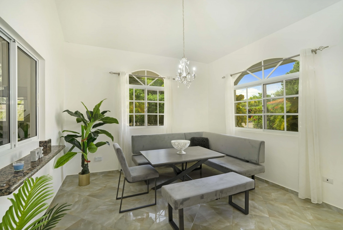 buyDRproperty Dining area in a beautiful villa with gray seating, a table, and a chandelier. Sosua Real Estate