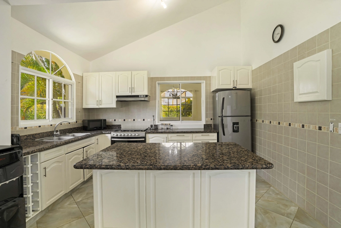 buyDRproperty Beautiful kitchen in the Hispaniola Residencial villa with white cabinets and granite countertops. Sosua Real Estate