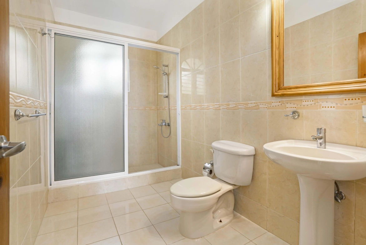 buyDRproperty Bathroom with shower, toilet, and sink, featuring tiled walls and floor. Sosua Real Estate
