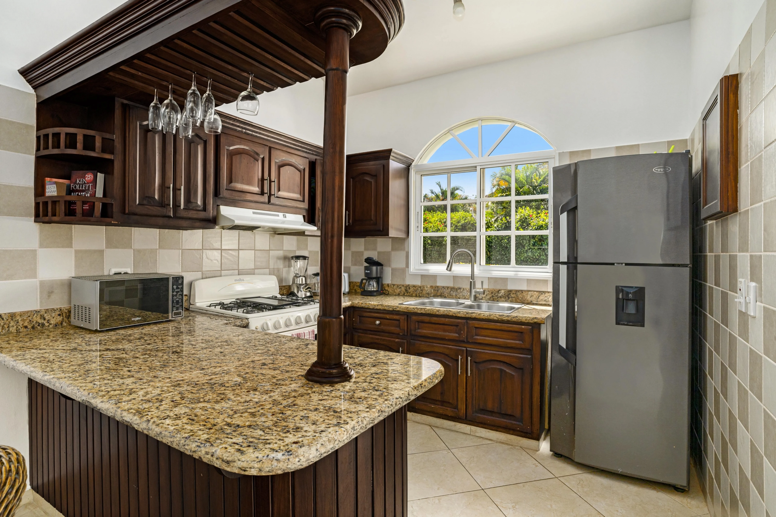 buyDRproperty Oversized kitchen with dark wood cabinets, granite countertops, and stainless steel refrigerator. Sosua Real Estate
